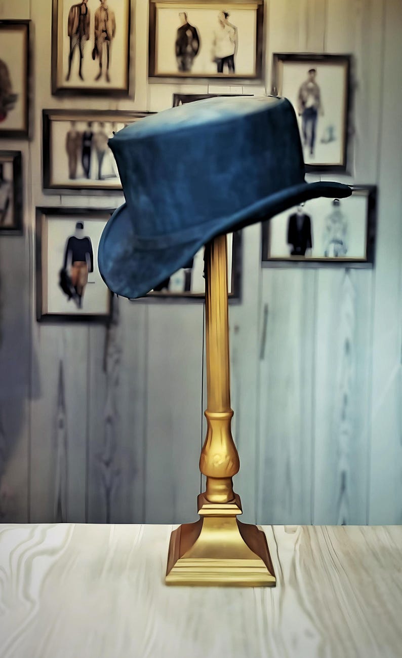 May include: A dark blue top hat rests on a gold-colored hat stand. The stand has a decorative base and a tall, slender stem. The background features framed pictures of people in suits, creating a vintage aesthetic.