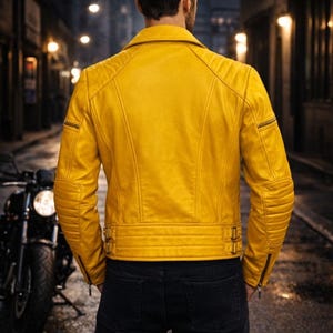 Back view of a handmade yellow leather biker jacket showing a clean rear leather panel and structured shoulder construction. The cropped length, reinforced seams, and fitted waist detailing are visible from the back, emphasizing balance and durability. Photographed on a male model outdoors in a city night environment to present silhouette, craftsmanship, and bold moto-inspired styling for statement leatherwear buyers.