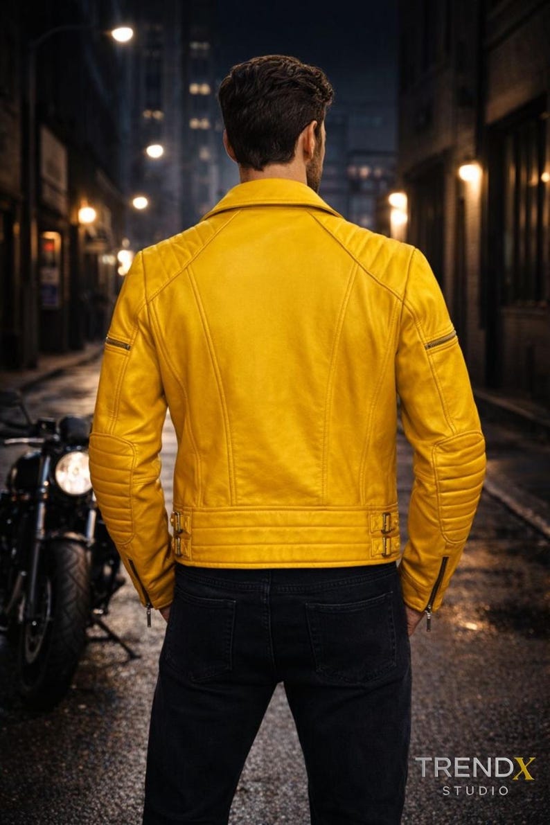 Back view of a handmade yellow leather biker jacket showing a clean rear leather panel and structured shoulder construction. The cropped length, reinforced seams, and fitted waist detailing are visible from the back, emphasizing balance and durability. Photographed on a male model outdoors in a city night environment to present silhouette, craftsmanship, and bold moto-inspired styling for statement leatherwear buyers.