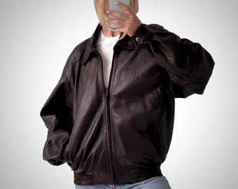 May include: A brown leather bomber jacket with a zipper closure and a ribbed hem.