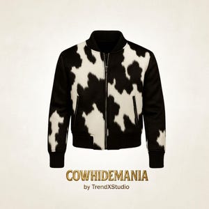 Op de afbeelding: Een zwart-witte bomberjack van koeienhuid met een ritssluiting, zwarte mouwen en een zwarte geribbelde kraag en manchetten. De jas heeft een koeienhuidpatroon en de tekst "COWHIDEMANIA by TrendXStudio" onderaan.
