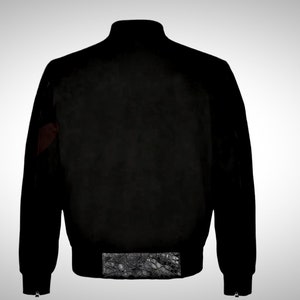 May include: A black bomber jacket with a ribbed collar, cuffs, and waistband. The jacket has a zipper closure and two pockets on the front. The sleeves have a red and black patterned detail.