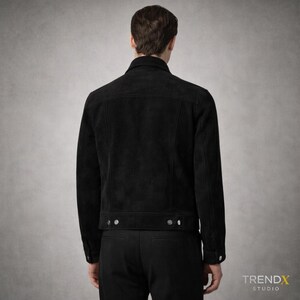 May include: Black suede jacket with a classic collar and button fastenings. The jacket features two chest pockets and a tailored fit. The back view highlights the jacket's design and stitching details. The jacket is from the TRENDX STUDIO collection.