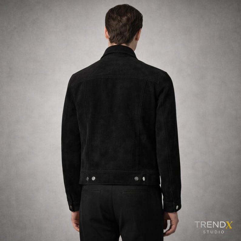May include: Black suede jacket with a classic collar and button fastenings. The jacket features two chest pockets and a tailored fit. The back view highlights the jacket's design and stitching details. The jacket is from the TRENDX STUDIO collection.