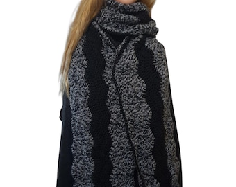May include: A handmade, black and gray crochet scarf. The scarf features alternating vertical stripes of solid black and textured gray yarn. The scarf is draped around a mannequin's neck and shoulders, showcasing its design and texture.