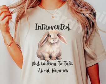 May include: A beige t-shirt with a graphic of a brown bunny and the text "Introverted. But Willing To Talk About Bunnies".