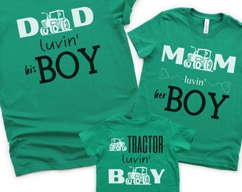 Può includere: Tre magliette verdi con un design di trattore e il testo "Dad luvin' his boy", "Mom luvin' her boy" e "Tractor luvin' boy".