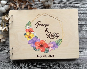 Könnte beinhalten: Ein Gästebuch aus Holz mit einem floralen Design und einem goldenen geometrischen Rahmen. Die Namen "George & Kathy" und das Datum "July 28, 2024" sind in Maroon gedruckt.