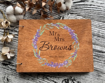 Könnte beinhalten: Ein Gästebuch aus Holz mit einem Design aus einem Lavendelkranz. Das Buch ist personalisiert mit dem Text "Mr. & Mrs. Browns" und dem Datum "May 19, 2018".