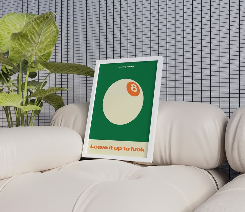 May include: A white framed print with a green background and a white circle with an orange number 8 in the center. The text "Leave it up to luck" is below the circle.