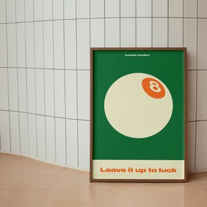 May include: A framed poster with a green background and a white 8-ball with an orange number 8. The text "Leave it up to luck" is printed below the 8-ball.