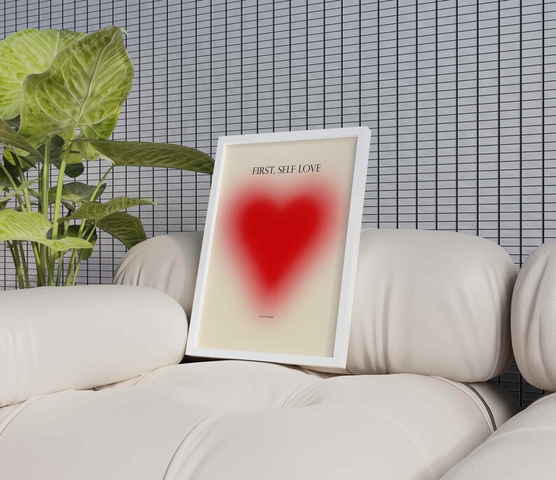 May include: A white framed print with the text "FIRST, SELF LOVE" and a red heart graphic. The print is sitting on a white couch.