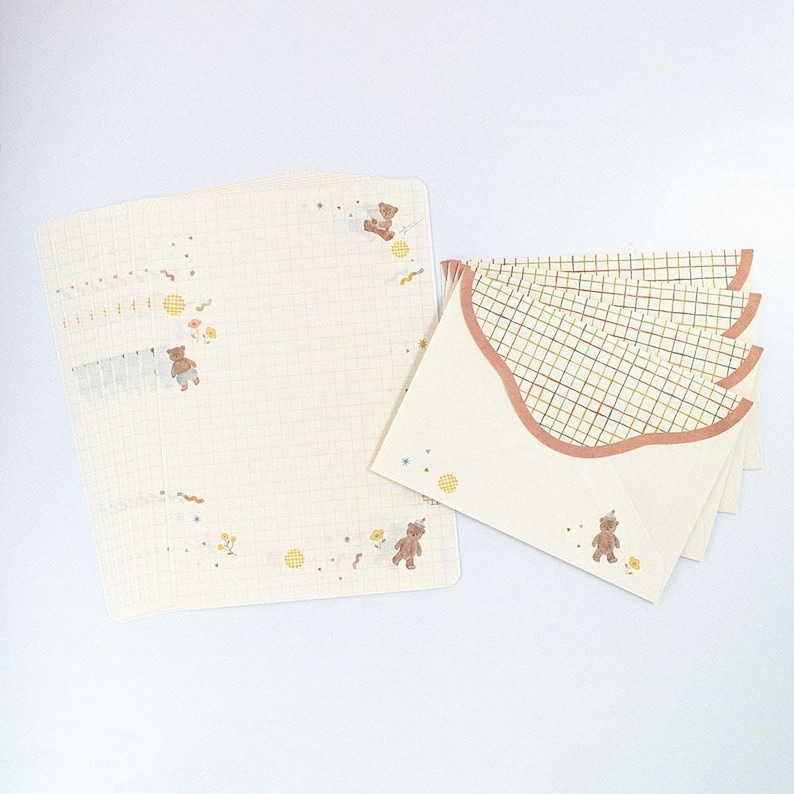 May include: Set of stationery featuring a grid pattern and illustrations of bears. The paper is cream colored with a light brown grid pattern. The envelopes are cream colored with a brown grid pattern and a scalloped edge.