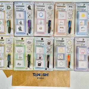 May include: A collection of Hancoco slide stamps in various designs, including circles, animals, and food items. Each package contains multiple stamps and a pen-like applicator. The packaging features the text "Hancoco slide" and "TANOSHI STUDIO".
