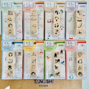 May include: A collection of wooden stamps featuring various animal illustrations, including a panda, cat, and rabbit. Each stamp is packaged with a calendar-style backing, and the text "TANOSHI STUDIO" is visible.