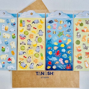 May include: Four sheets of stickers with a summer theme. The first sheet features polar bears and tropical drinks on a blue background. The second sheet features penguins and fruit on a yellow background. The third sheet features fish and sea creatures on a blue background. The fourth sheet features dogs and watermelons on a green background. All sheets have the text "Summer Selection" on them.