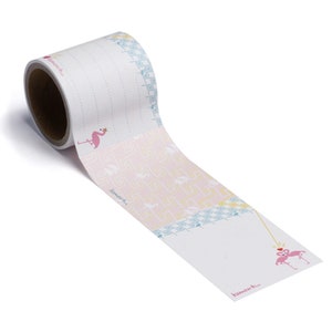 May include: A roll of pink and blue patterned washi tape with flamingo illustrations. The tape features a repeating pattern of pink flamingos with yellow crowns and a blue and yellow geometric design. The text "komono+" is printed on the tape.