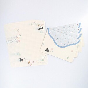 May include: A set of stationery featuring a black cat and ice cream cone design. The paper is white with a grid pattern and the envelopes have a blue scalloped edge with a confetti pattern.