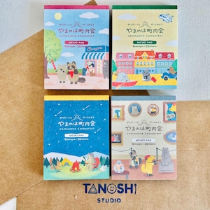 May include: Four colorful memo pads with Japanese text and illustrations of animals and scenes. Each pad has a different design, including a town, camping, and art gallery. The pads are labeled "MEMO PAD" and "YAMANOHA CHOHAIRAI". The Tanoshi Studio logo is at the bottom.