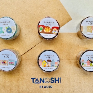 May include: Six rolls of masking tape with various designs, including floral patterns, food illustrations, and townscapes. Each roll has the words "masking tape" and "Made in Japan" printed on it. The Tanoshi Studio logo is at the bottom.