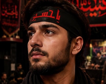 May include: A person wearing a black headband with red Arabic script. The person has dark hair and a beard, and is wearing a black shirt. The background is dark with some blurred figures.