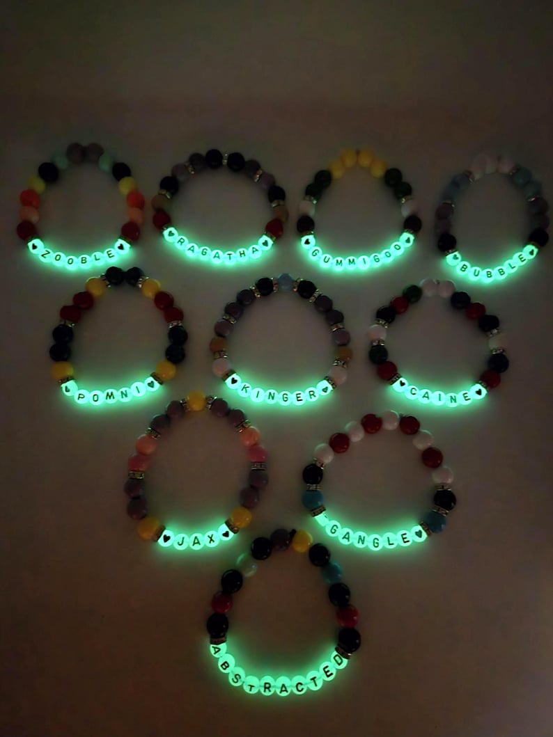 Peut inclure: Collection de dix bracelets de perles avec des perles de lettres blanches lumineuses &eacute;pelant des noms tels que "ZOOBLE", "RAGATHA" et "GUMMIGOO". Les bracelets pr&eacute;sentent une vari&eacute;t&eacute; de perles color&eacute;es, dont le rouge, le noir, le jaune et le bleu.