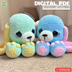 Puede incluir: Dos juguetes de perro de peluche de ganchillo. Uno es azul claro y amarillo, el otro es azul y rosa. Los juguetes tienen grandes ojos negros y hocicos blancos. El texto "DIGITAL PDF CROCHET PATTERN" está en la parte superior.