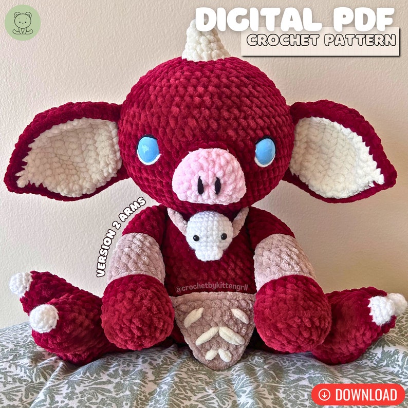 May include: A crocheted plush toy in the shape of a red and white pig with a horn. The toy has blue eyes and a pink nose. The toy is holding a smaller white crocheted toy. The image includes the text "DIGITAL PDF CROCHET PATTERN" and "VERSION 2 ARMS".