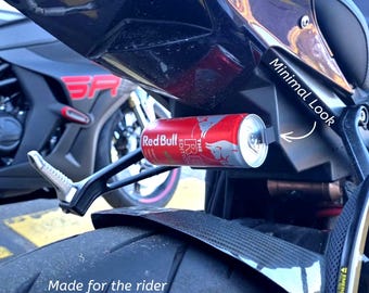 May include: A motorcycle with a Red Bull can holder attached. The can is red and silver, with the Red Bull logo visible. The text "Minimal Look" is written on the motorcycle. The text "Made for the rider" and "Tested in Old Pacific Highway, NSW" is also visible.