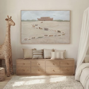 May include: A rectangular wall art print in a light wood frame depicting a large wooden ark resting on a sandy hill with a procession of various animals walking toward it. The scene features giraffes, elephants, lions, and other wildlife.