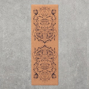 May include: A cork yoga mat with a black and white mandala design featuring an eye and geometric shapes. The design is repeated twice on the mat.