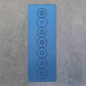 May include: A blue yoga mat with seven chakra symbols printed on it. The symbols are in a vertical line down the center of the mat.