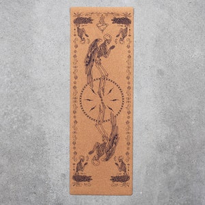 May include: A brown cork yoga mat with a black and white illustration of two skeletons with wings, a heart, and a circle with lightning bolts. The mat has a decorative border.
