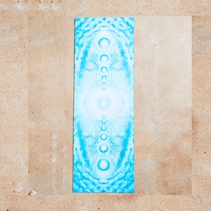 May include: A blue yoga mat with a white and blue mandala design. The design features a central circle with a series of concentric circles and dots radiating outwards.