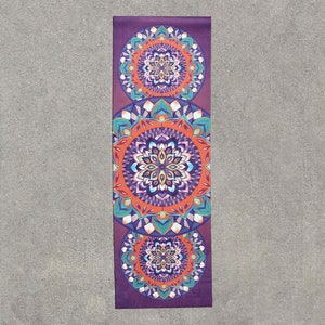 May include: A purple yoga mat with three colorful mandala designs. The mandalas are in shades of orange, blue, green, and white.