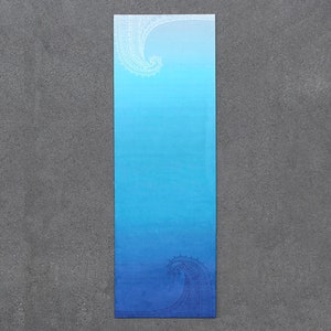 May include: A blue yoga mat with a white and blue gradient design. The design features two stylized waves, one at the top and one at the bottom of the mat.