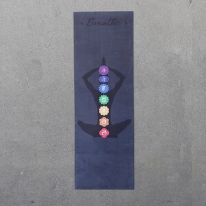 May include: A black yoga mat with a silhouette of a person in a yoga pose. The mat has seven colorful circles representing the seven chakras, with the word "Breathe" at the top.