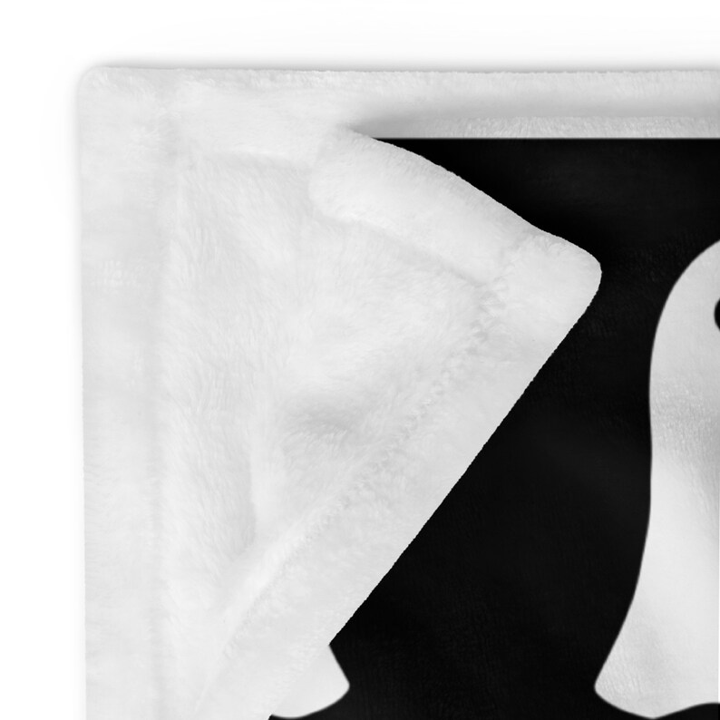 May include: A white plush blanket with a black background featuring a white silhouette of a ghost.