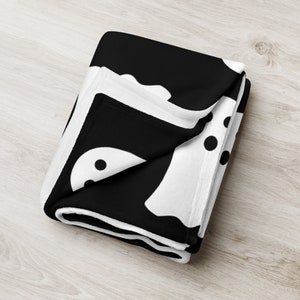 May include: Black and white fleece throw blanket with a pattern of ghosts and polka dots.