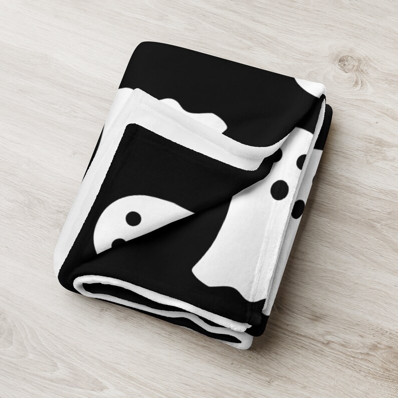 May include: Black and white fleece throw blanket with a pattern of ghosts and polka dots.