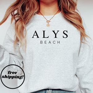 May include: A gray sweatshirt with the text "ALYS BEACH" printed on the front in black.