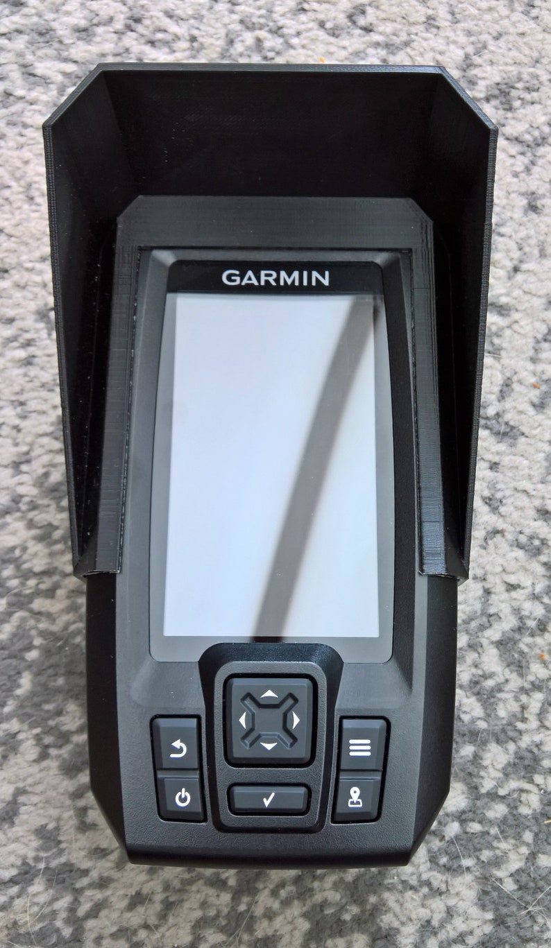 May include: Black Garmin fish finder with a protective visor. The device has a screen and several buttons. The word "GARMIN" is printed on the top of the device.