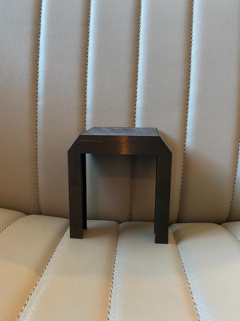 May include: A small, dark brown wooden side table with a square top and four straight legs. The table is made of a dark wood and has a simple, modern design. The table is approximately 30 cm tall.
