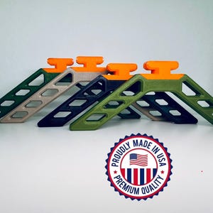 May include: Four colorful, angled, plastic stands with an orange top and a series of diamond-shaped cutouts. The stands are in shades of green, tan, and navy blue. The image includes a circular emblem that reads "Proudly Made in USA, Premium Quality."