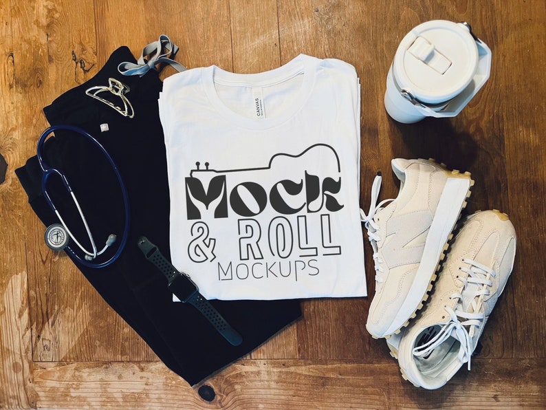 May include: White t-shirt with a black graphic that says "Mock & Roll Mockups" with a guitar design. The t-shirt is laid out on a wooden surface with a pair of white sneakers, a black scrub top, a stethoscope, a watch, and a white water bottle.