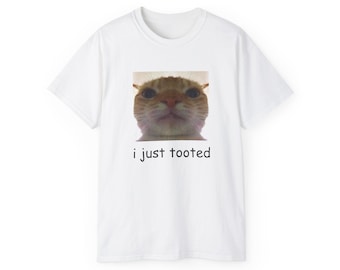May include: White t-shirt with a picture of a cat's face and the text "i just tooted" printed on it.