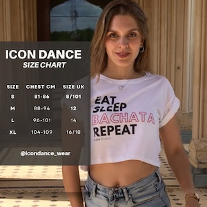 May include: White crop top with the text "Eat Sleep Bachata Repeat" in pink and black lettering. Size chart with chest measurements in centimeters and UK sizes.