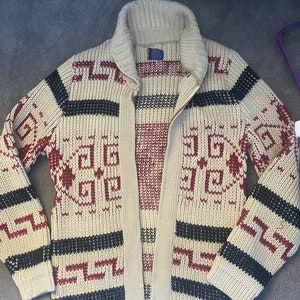 May include: A cream-coloured knitted cardigan with a zip fastening and a geometric pattern in black, red and white.