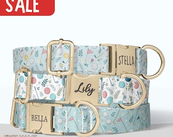 May include: Three dog collars with golf-themed patterns in light blue, white, and gold. The collars feature golf balls, flags, and clubs. Each collar has a gold buckle and a name engraved: Stella, Lily, and Bella. The word "SALE" is in a red box.