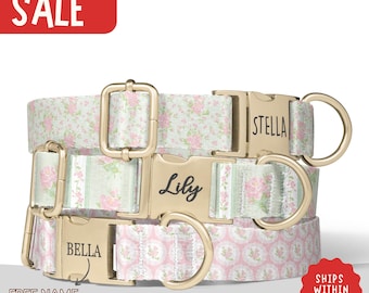 May include: Three dog collars with floral patterns and gold-coloured metalwork. The collars feature white fabric with pink roses and green leaves. Each collar has a name engraved on the buckle: Lily, Stella, and Bella. The image includes the text "SALE" and "FREE NAME ENGRAVING".